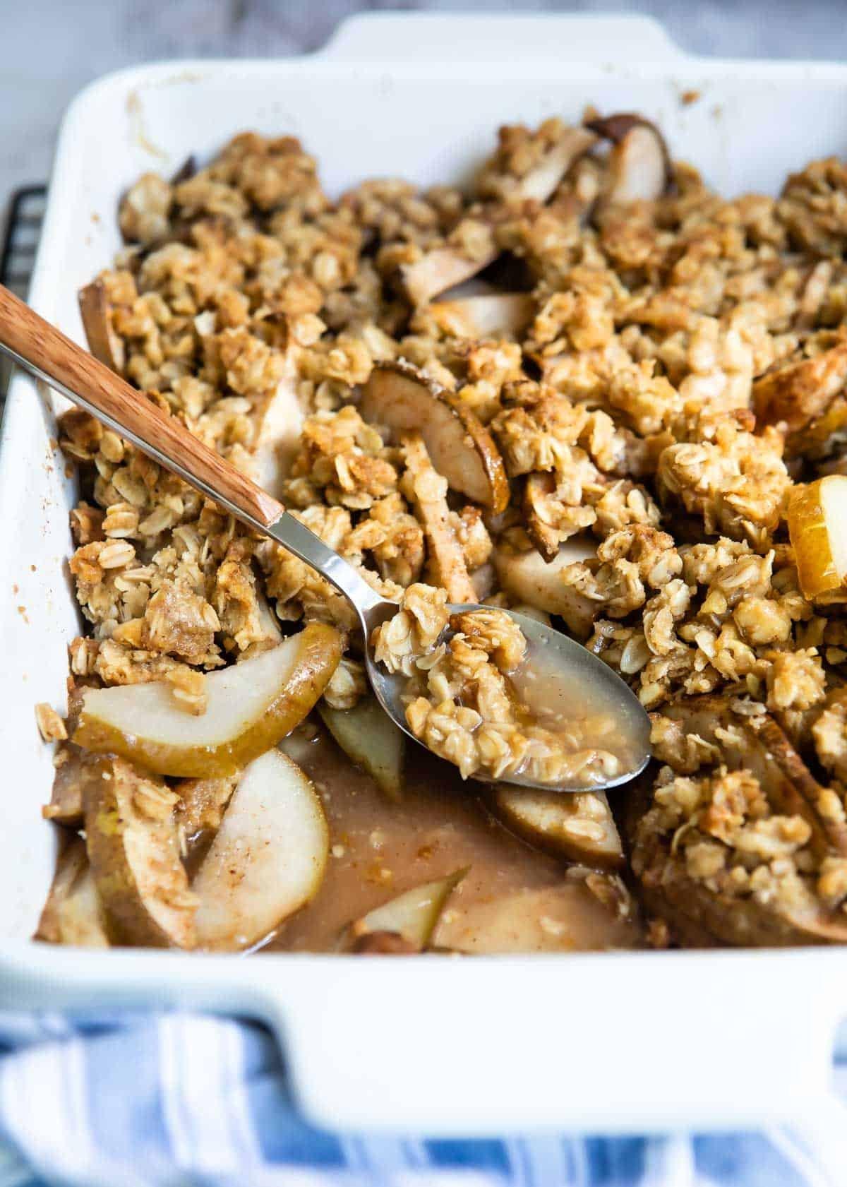 Pear crisp with dates and walnuts, golden brown and bubbling in a baking dish