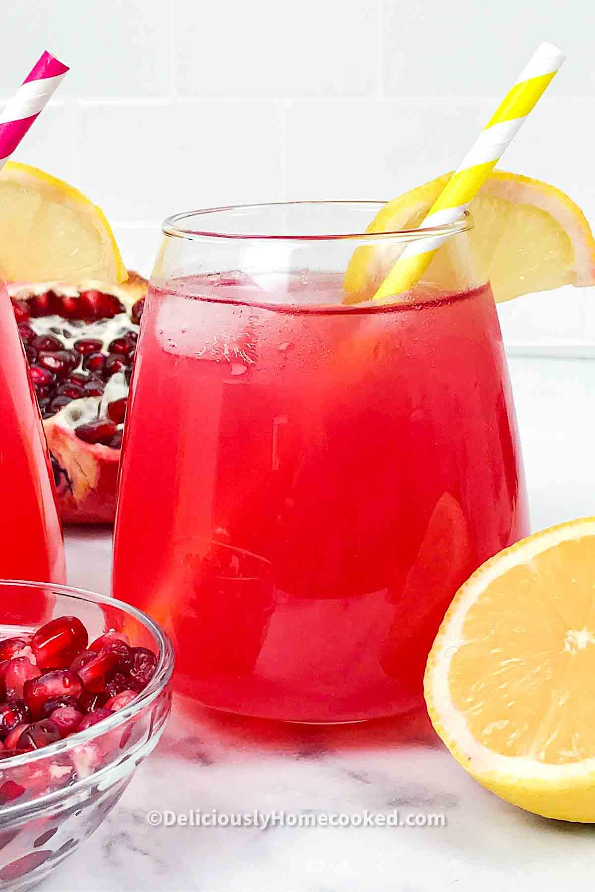 close-up of pomegranate seeds and lemon slices floating in a glass of lemonade showing the texture and colors