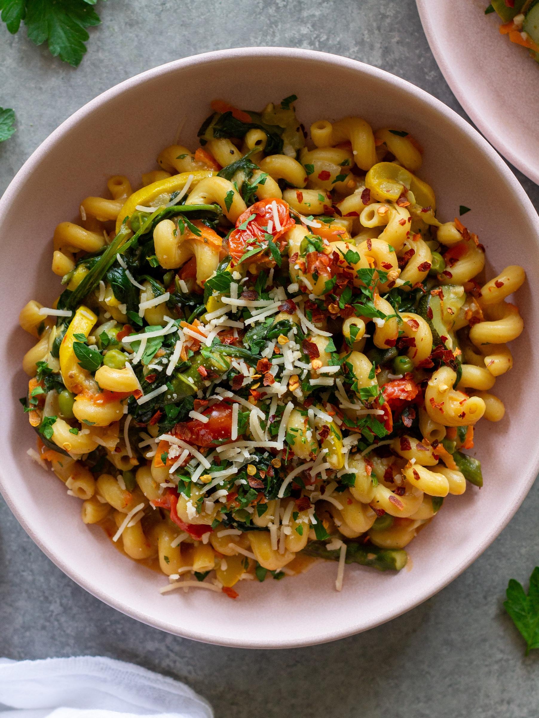 Close-up of one-pot pasta primavera with visible vegetables and steam rising