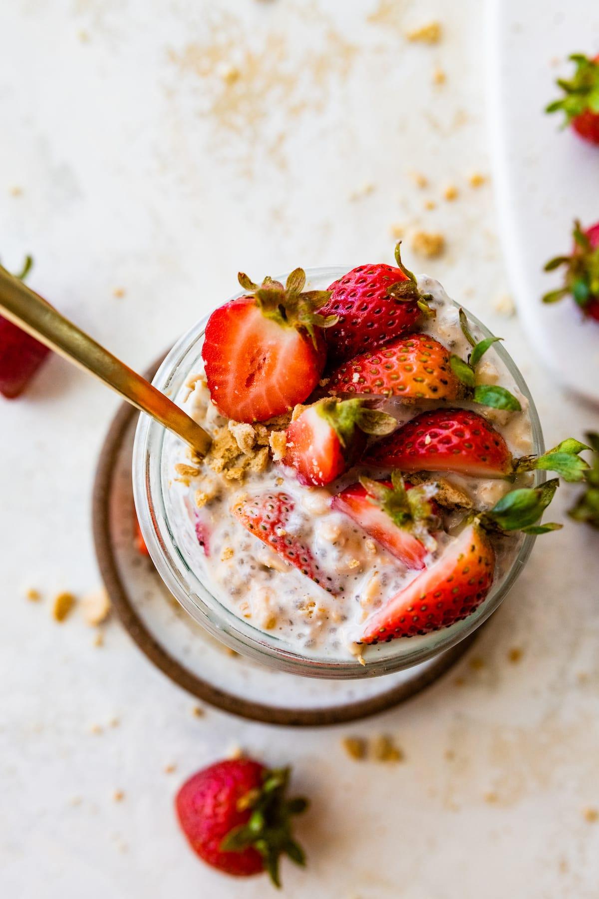 Close-up shot of a jar of strawberry swirl cheesecake overnight oats with a spoon