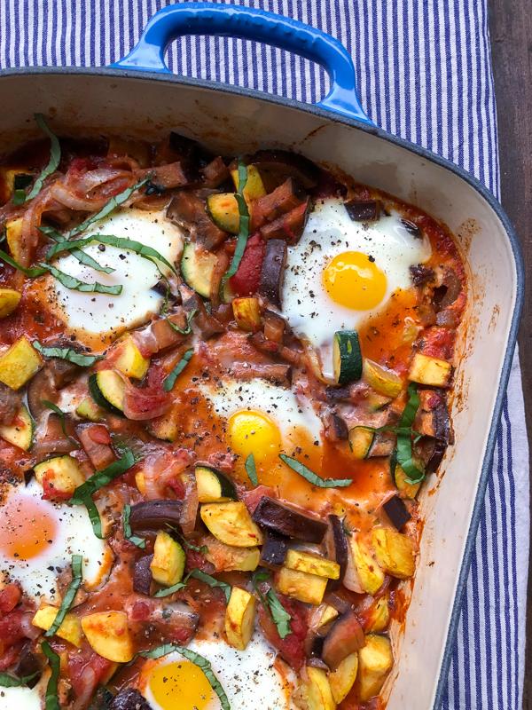 Close-up shot of a slice of Summer Ratatouille Breakfast Bake, showing layers of vegetables, cheese, and a perfectly cooked egg custard.