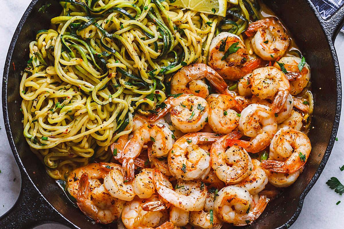 Garlic butter shrimp with zucchini noodles in a skillet, garnished with parsley