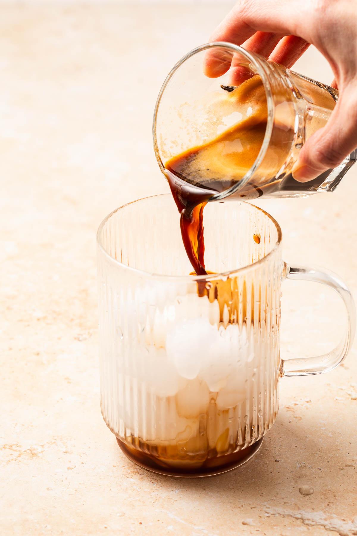 pouring cold brew into a glass with hemp milk