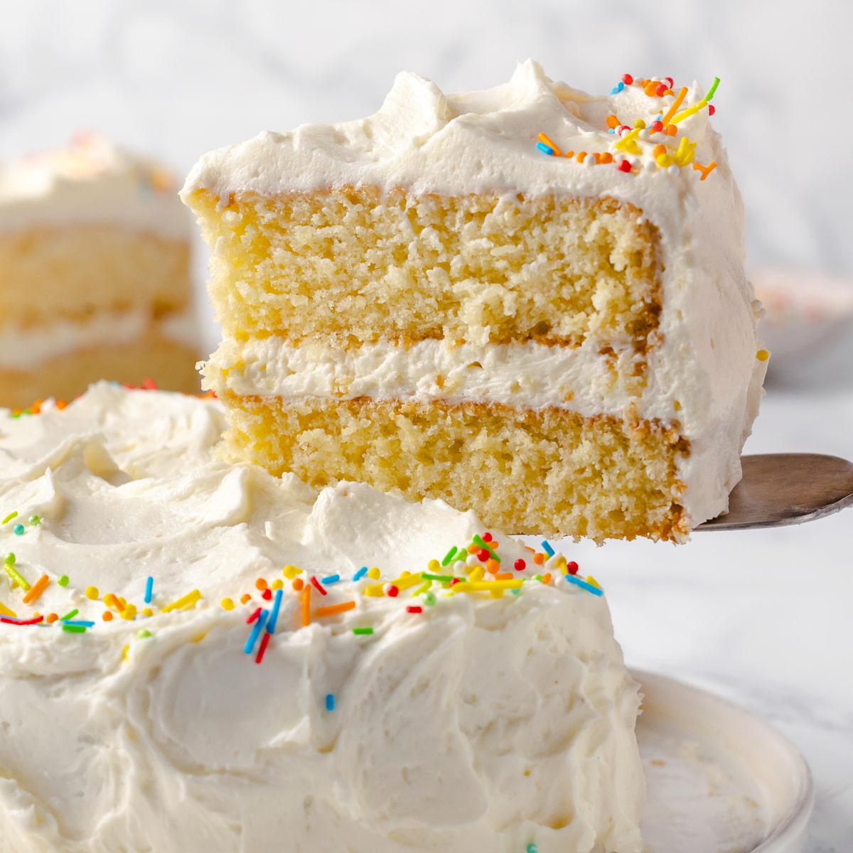 Close-up shot of a slice of vanilla cake with rice paper decorations, showing the moist crumb and delicate details
