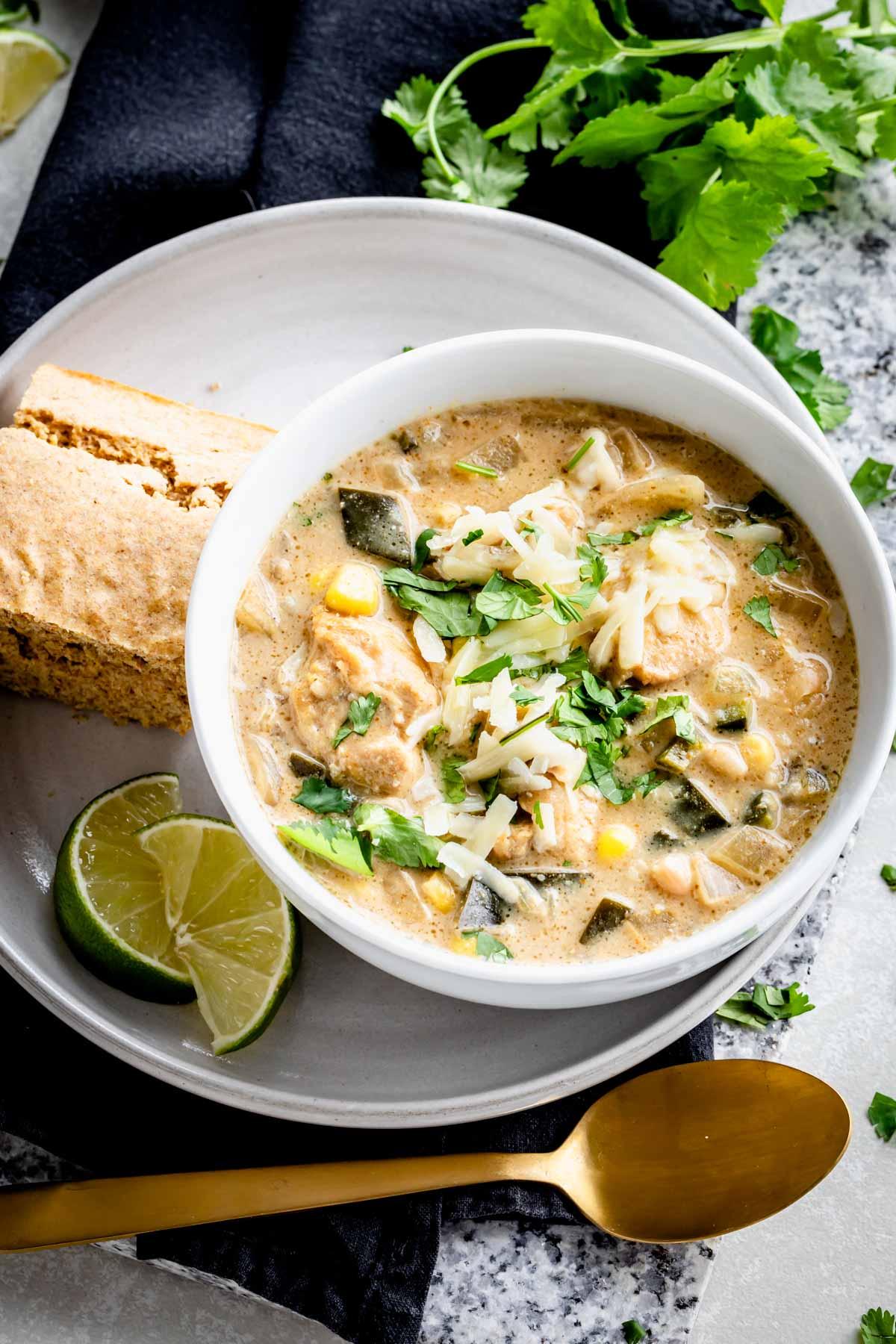 white chicken chili with mussels garnished with cilantro and lime wedges