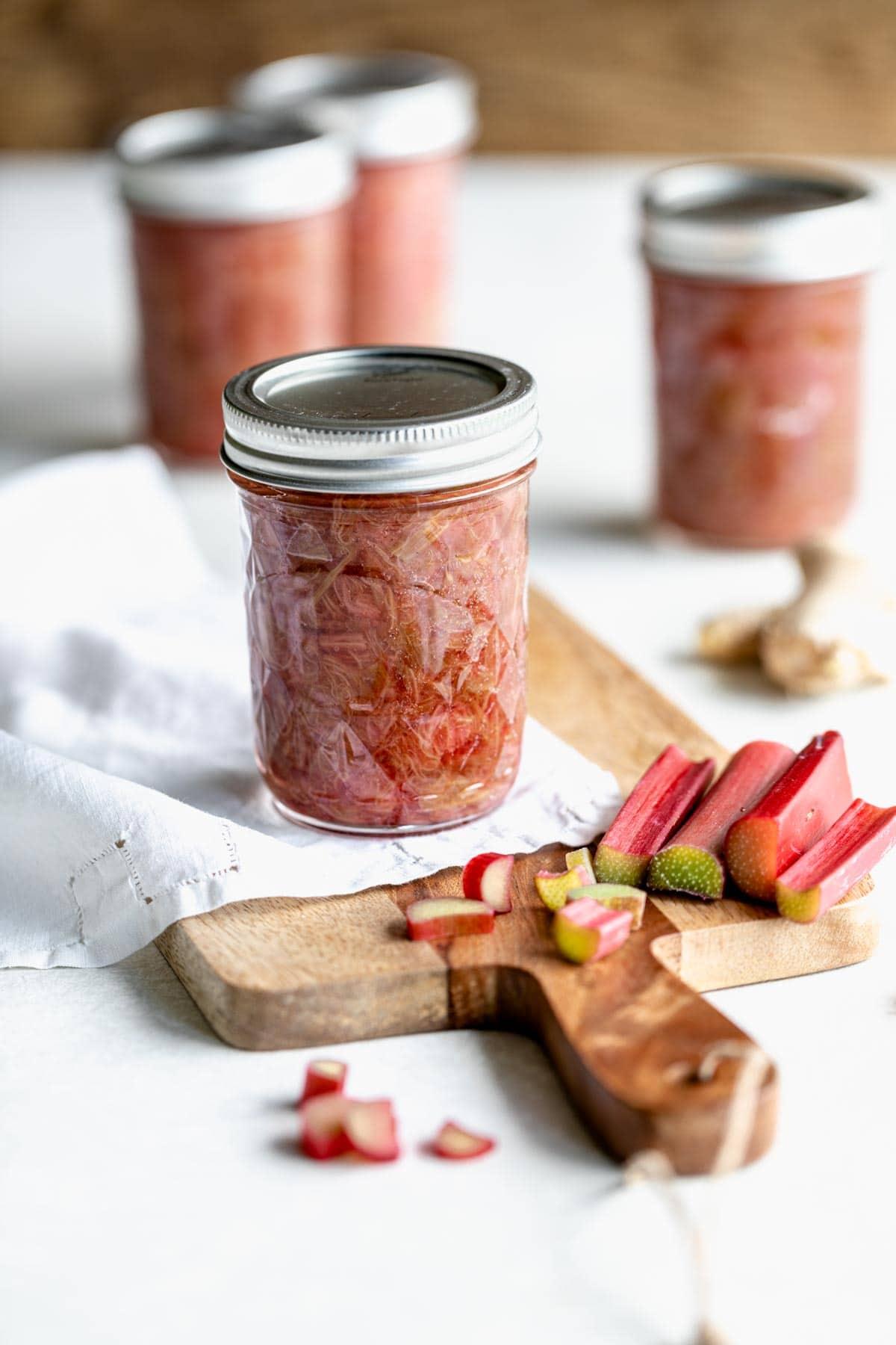 small jars of gingerbread rhubarb compote, tied with ribbons, on a wooden table