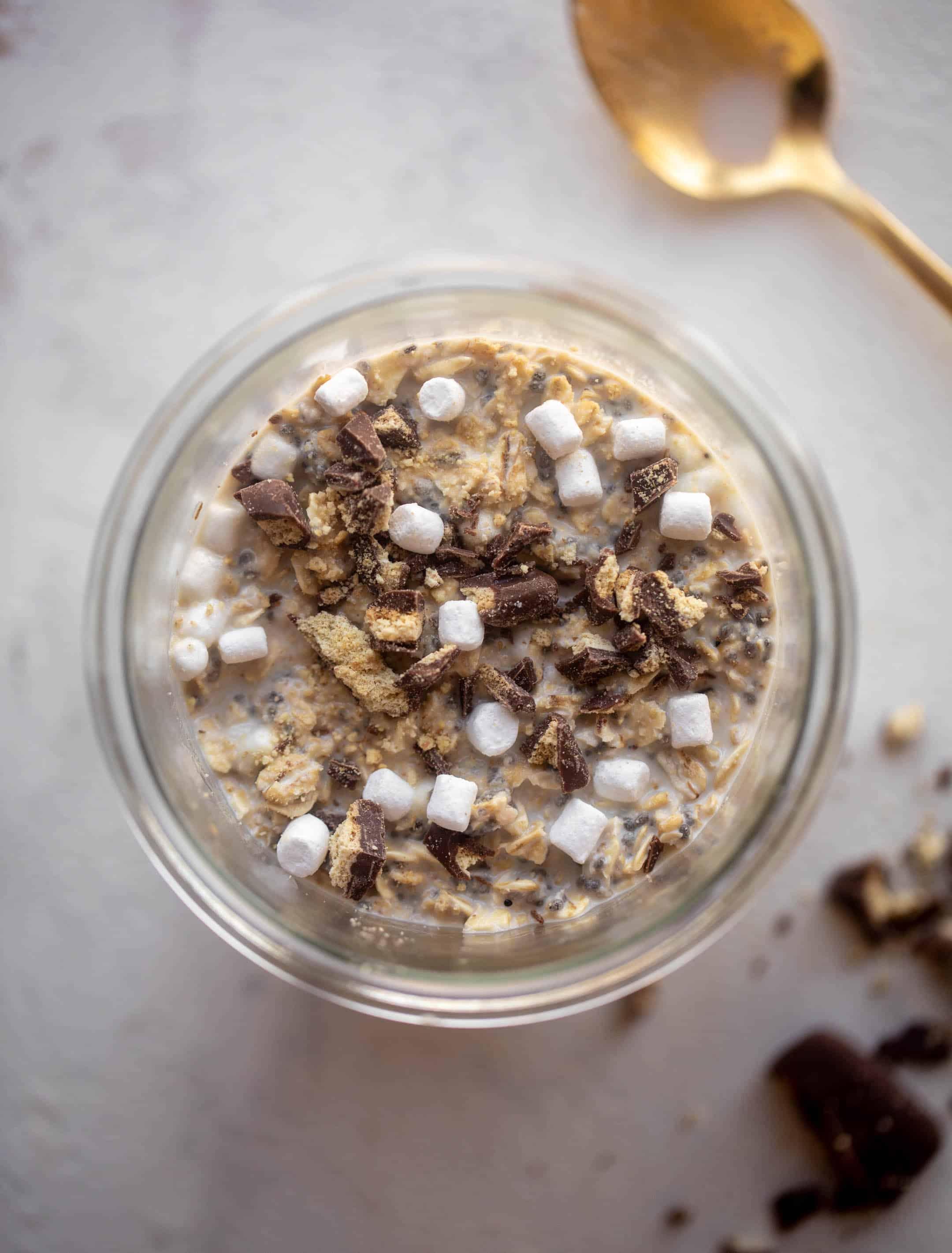 layered s'mores overnight oats in a clear jar, showing the different textures and ingredients