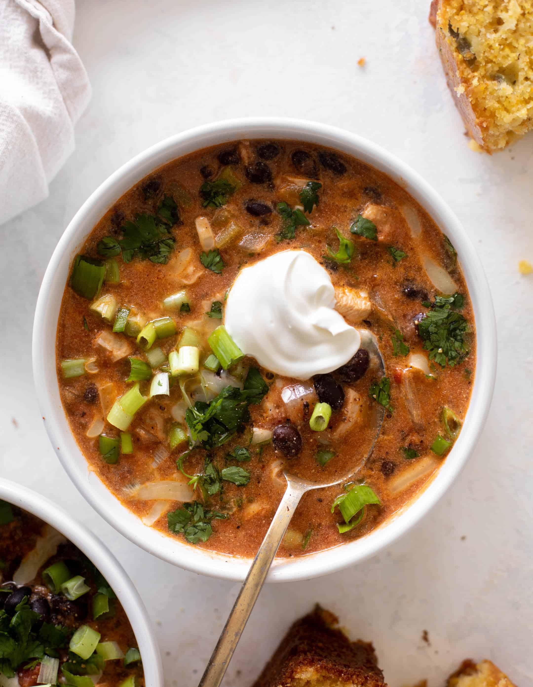 bowl of chicken and black bean chili topped with sour cream and cilantro