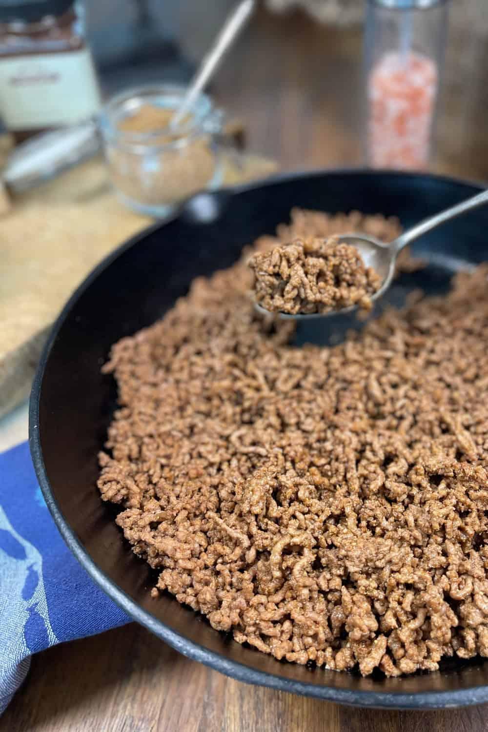 close-up shot of ground beef being seasoned with everything bagel seasoning in a skillet