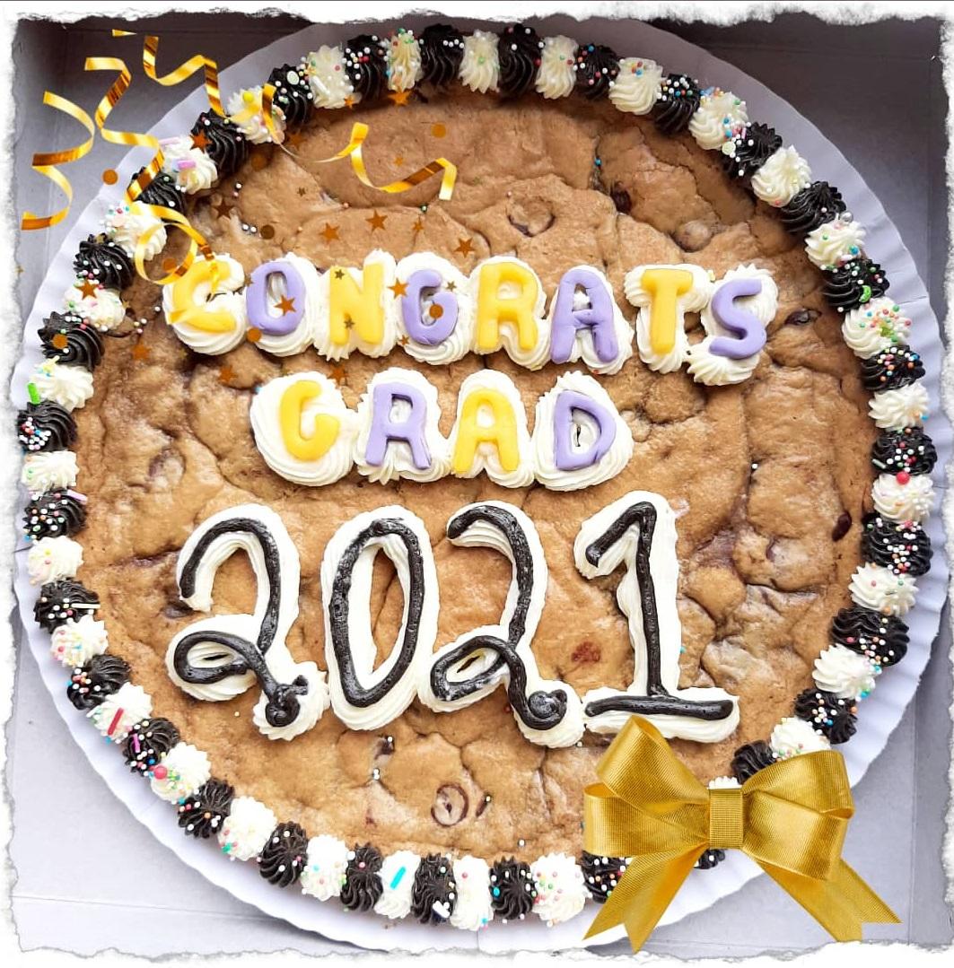 people holding slices of graduation cookie cake at an outdoor graduation party