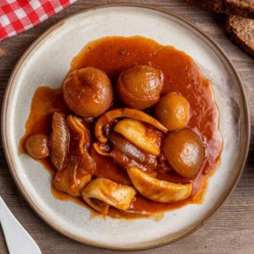 Finished cuttlefish stew served in a bowl with a side of crusty bread