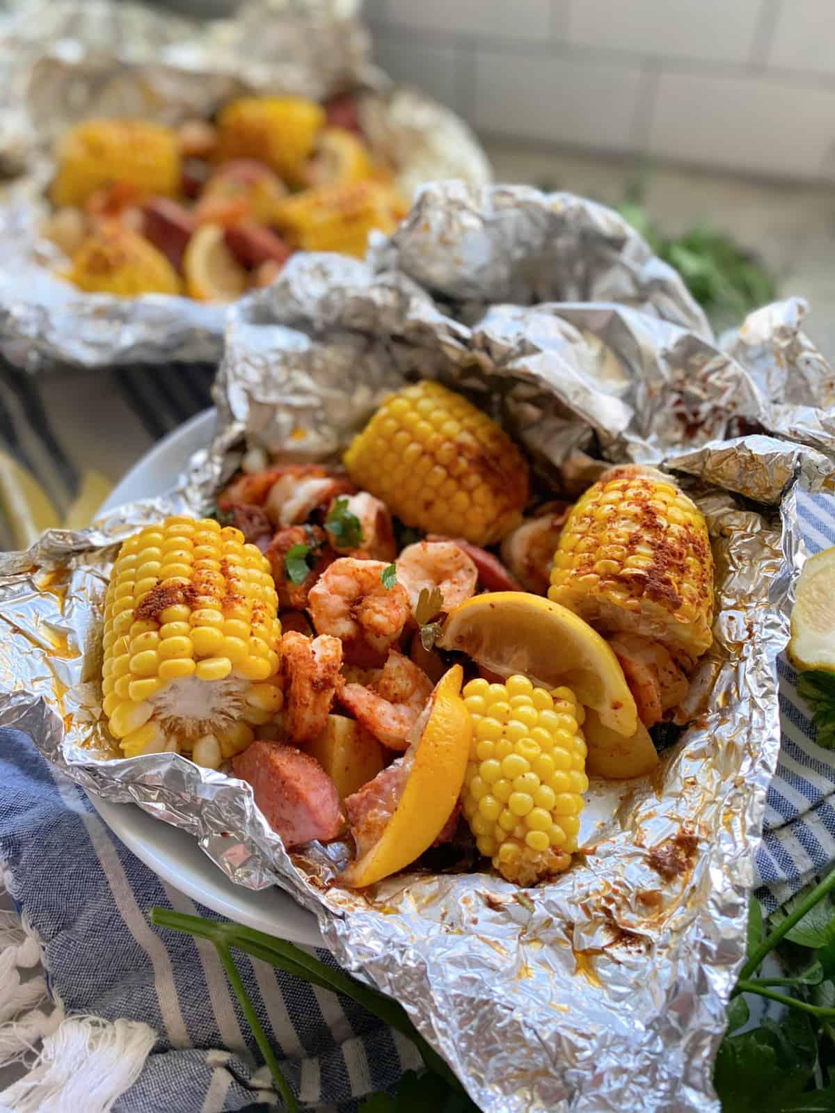 Close-up of opened foil packet revealing shrimp, sausage, potatoes, and corn