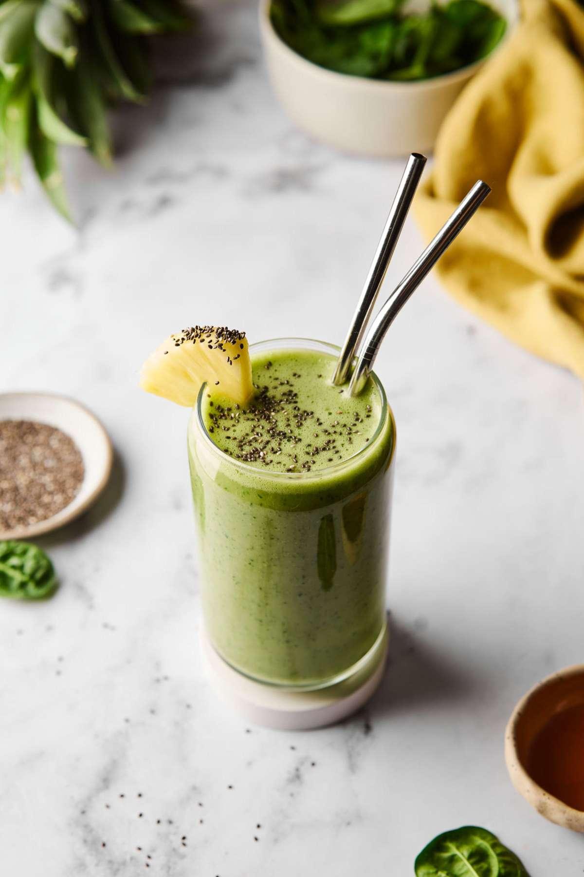 a vibrant green smoothie in a glass, garnished with hemp hearts and banana slices