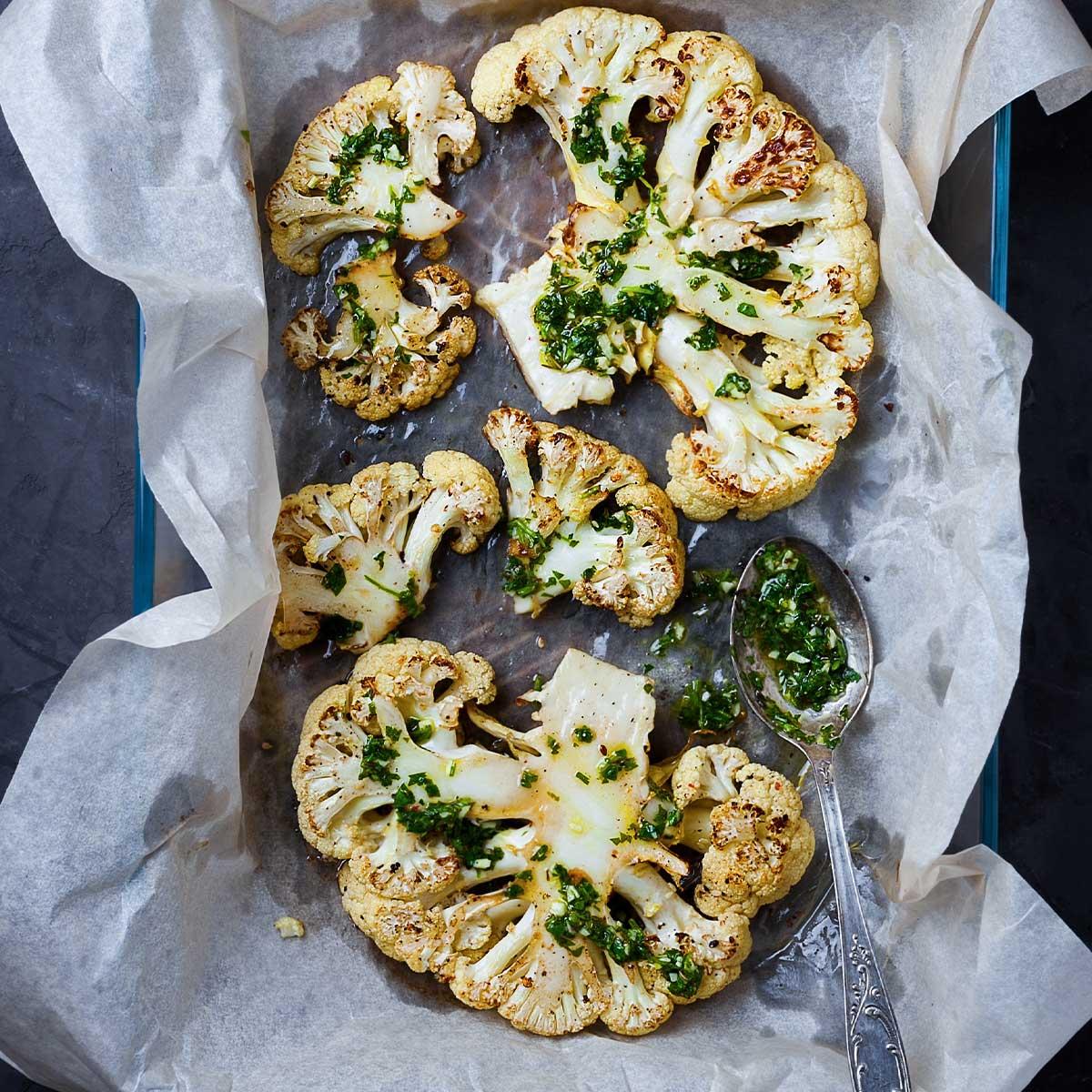 close up shot of garlic herb mixture being brushed onto a cauliflower steak
