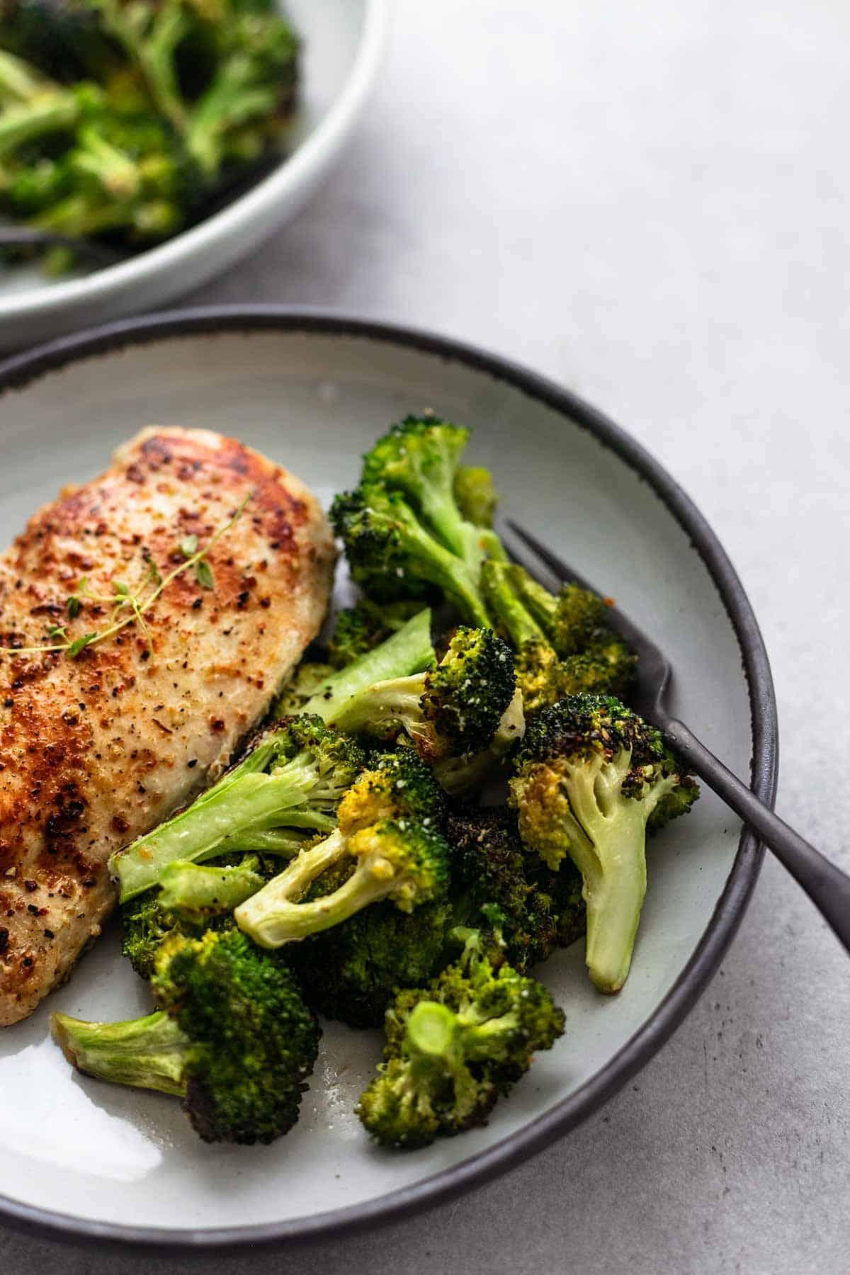 roasted chicken and broccoli on a plate with herbs