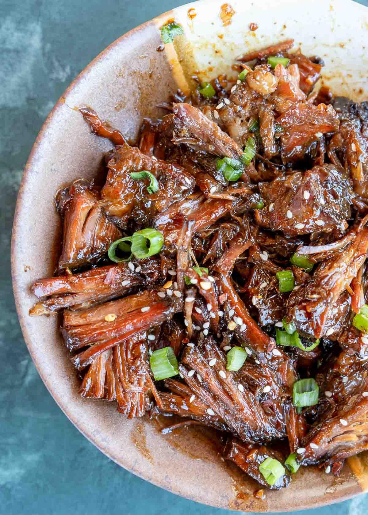 Close-up of slow-cooked beef cheek being shredded with forks