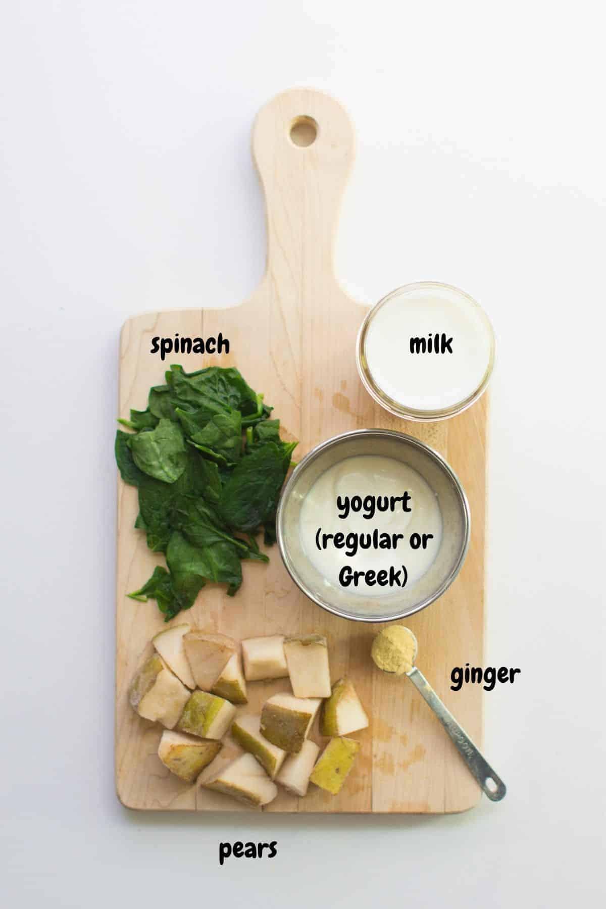 close up of green smoothie ingredients laid out on a wooden table