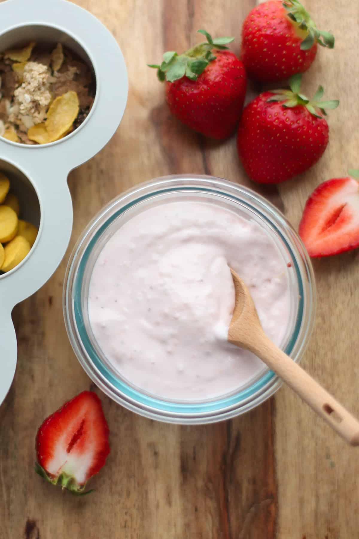 close-up shot of yogurt, milk, and fruit being prepared for blending