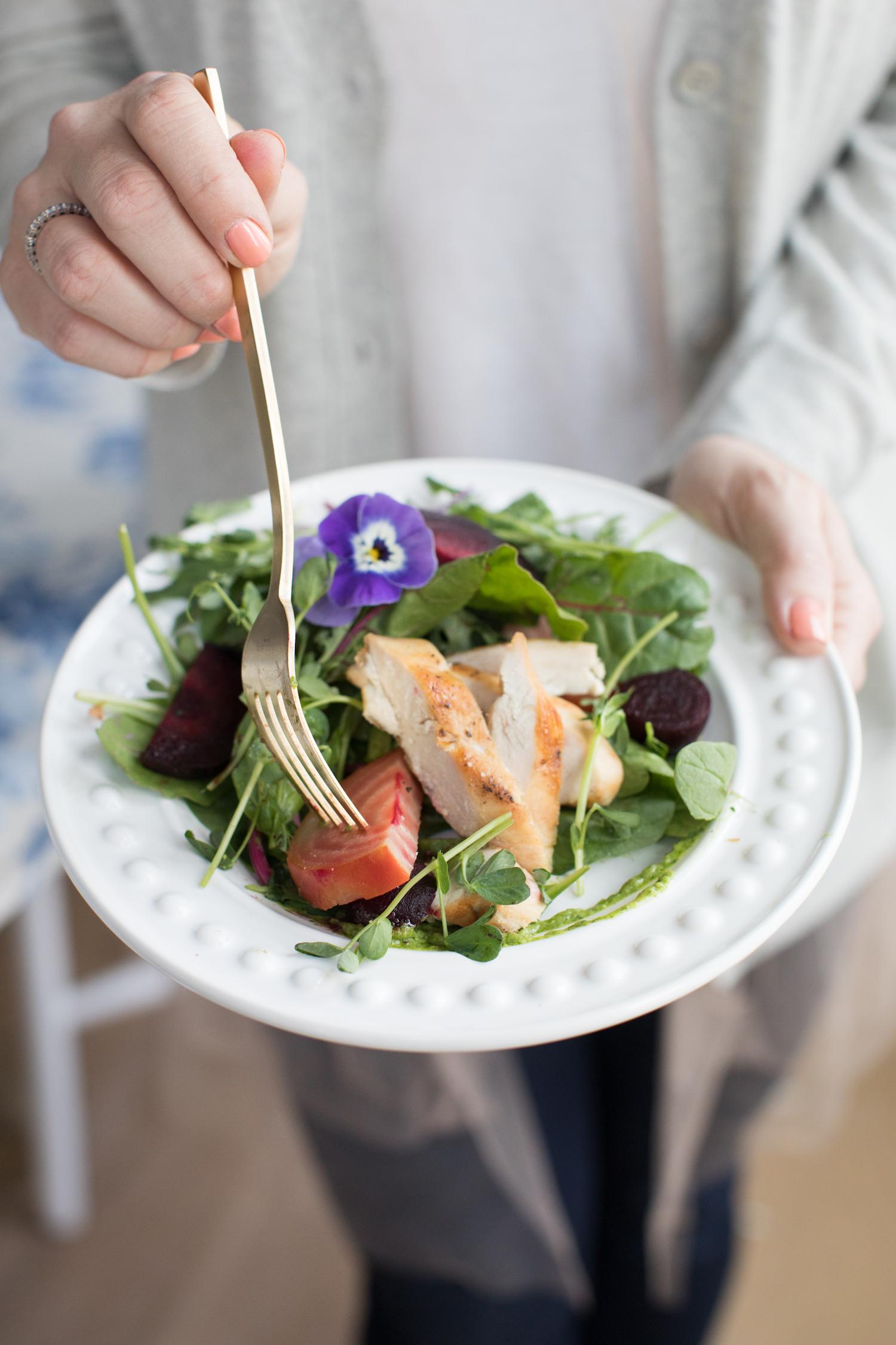 person preparing beet greens chicken salad in a kitchen