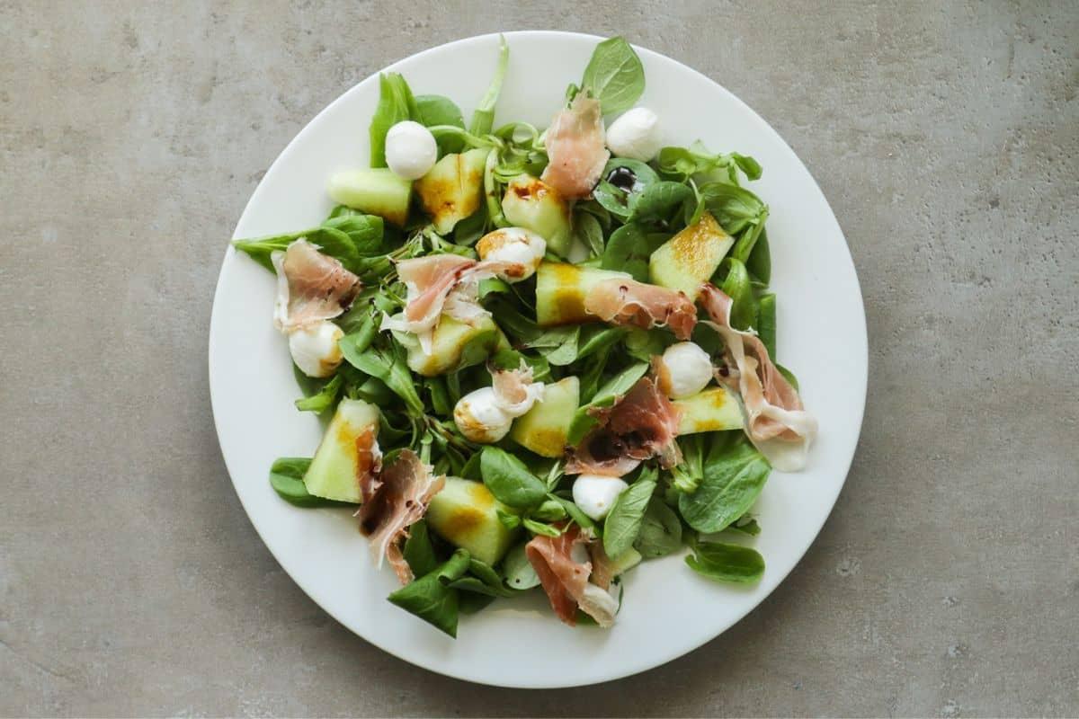 Overhead shot of watermelon fig prosciutto salad in a white bowl