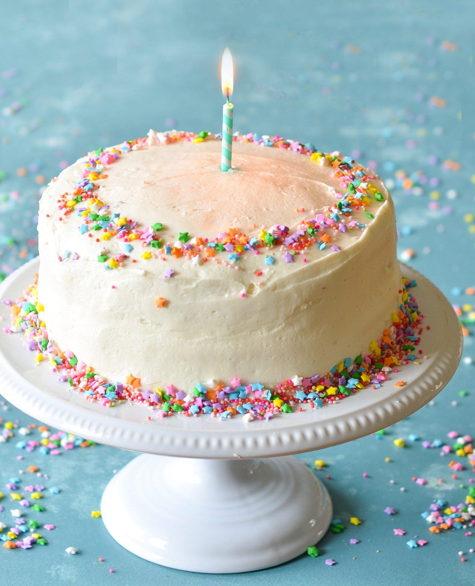 a vanilla birthday cake with colorful frosting and candles