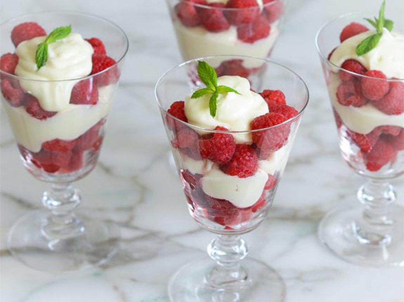 spoon scooping a layer of raspberries and cream yogurt parfait