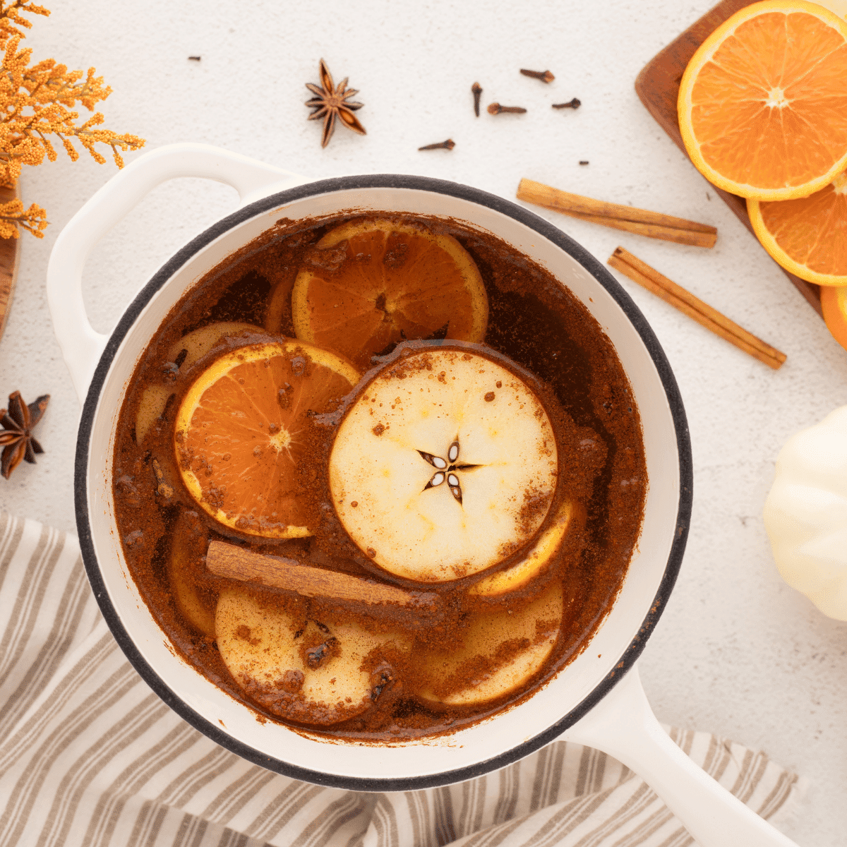 Close-up of fresh orange slices, cinnamon sticks, and star anise arranged beautifully for a simmer pot