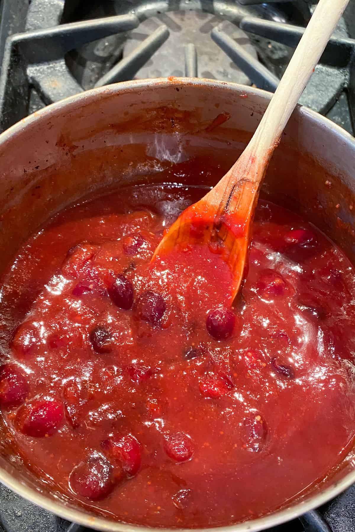 Close-up shot of homemade cranberry barbecue sauce simmering in a saucepan
