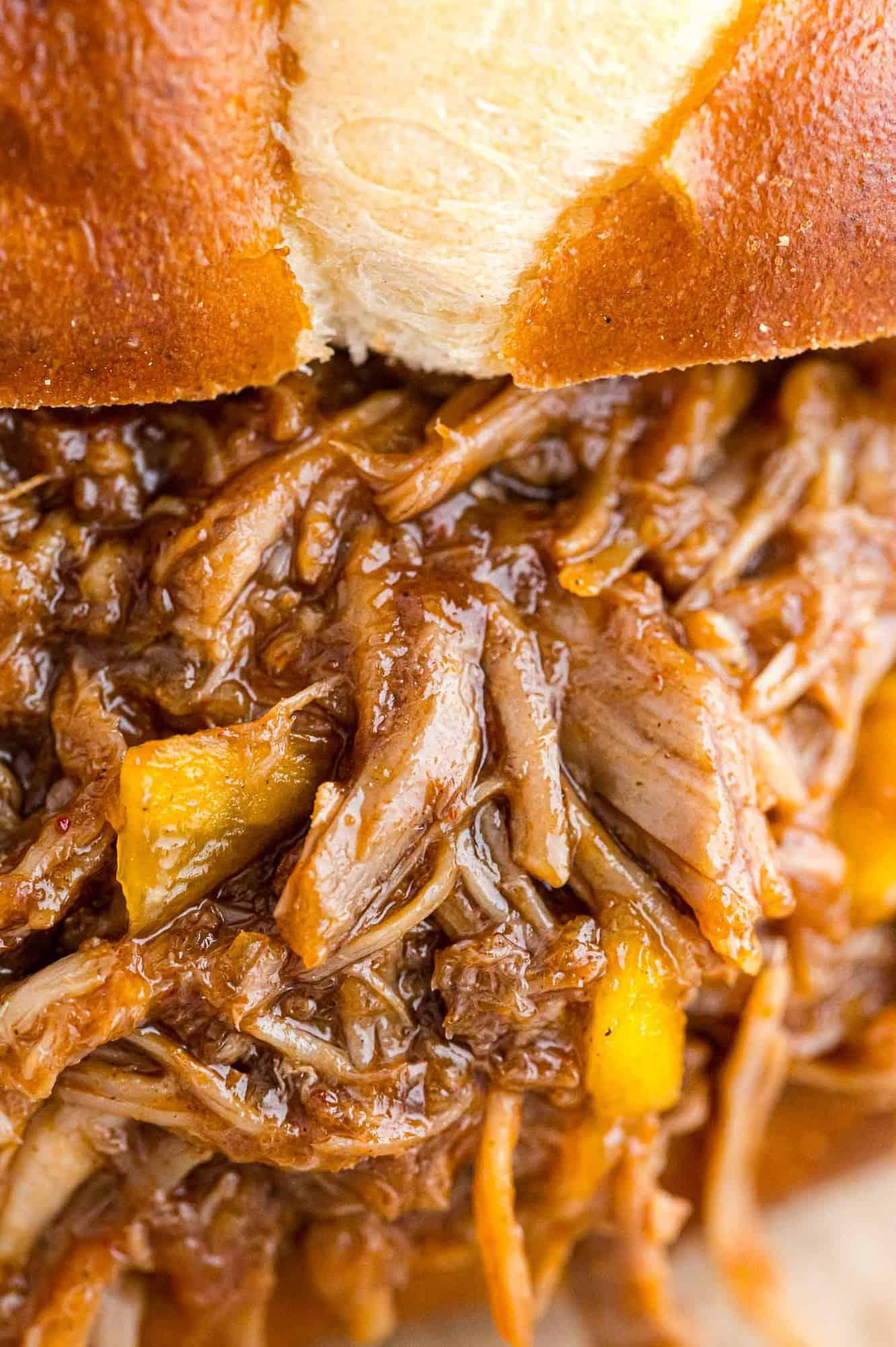 close up of pulled pork in slow cooker with mango salsa ingredients nearby