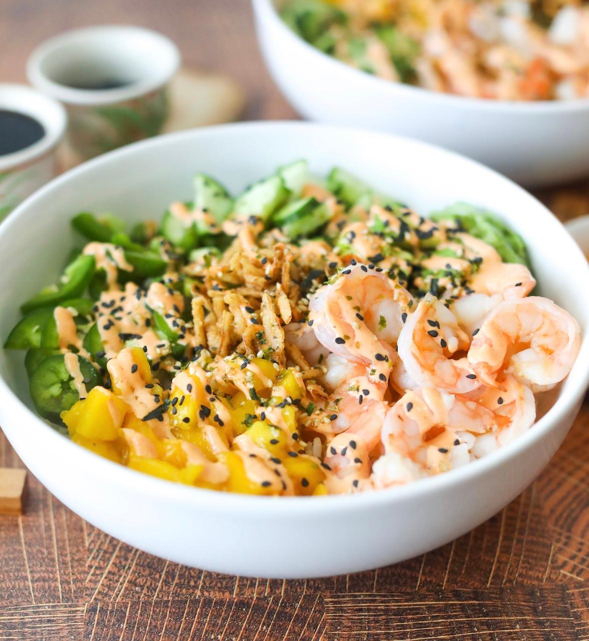 close up shot of a rainbow dragon roll deconstructed bowl with a spoon taking a scoop