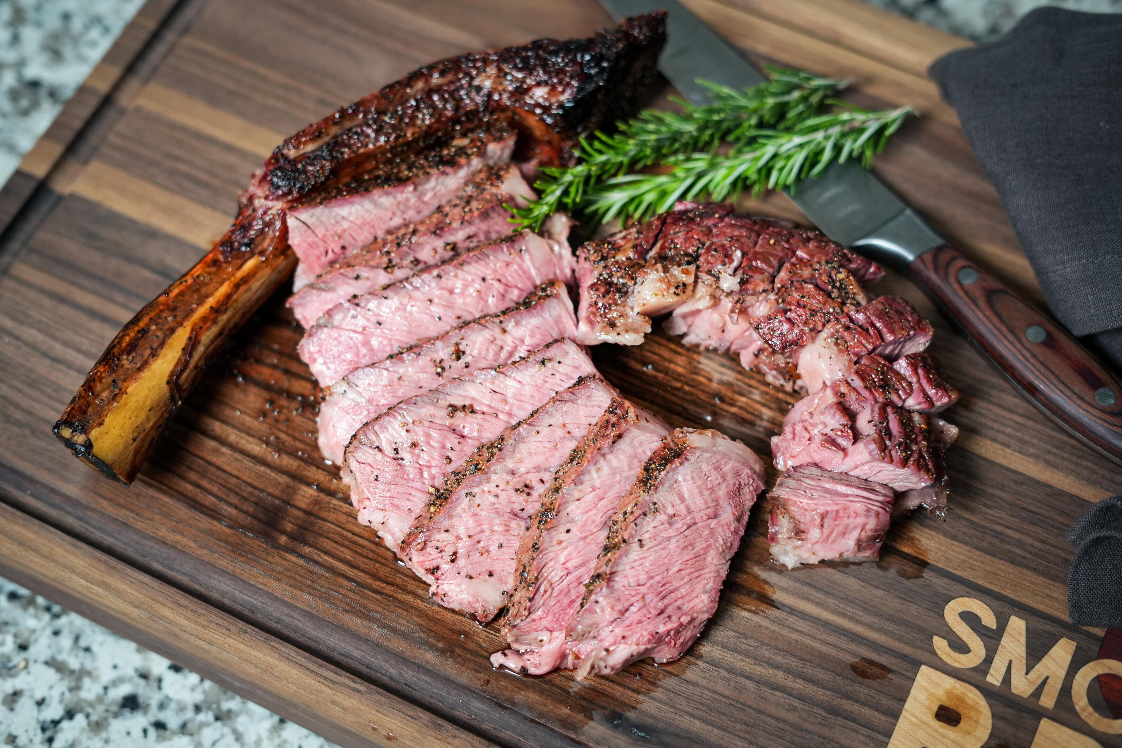 sliced reverse seared tomahawk steak on a cutting board