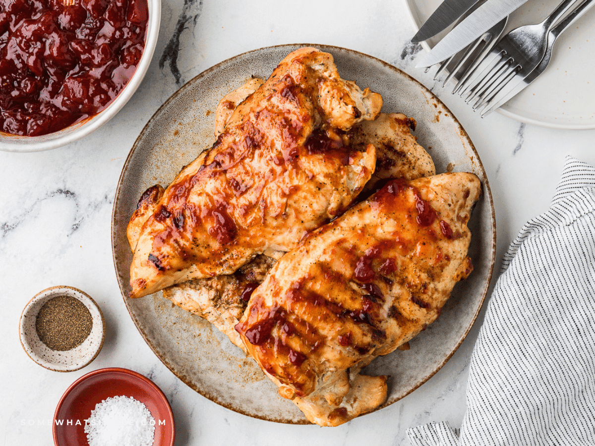 Overhead shot of cranberry barbecue chicken on a platter with fall foliage in the background