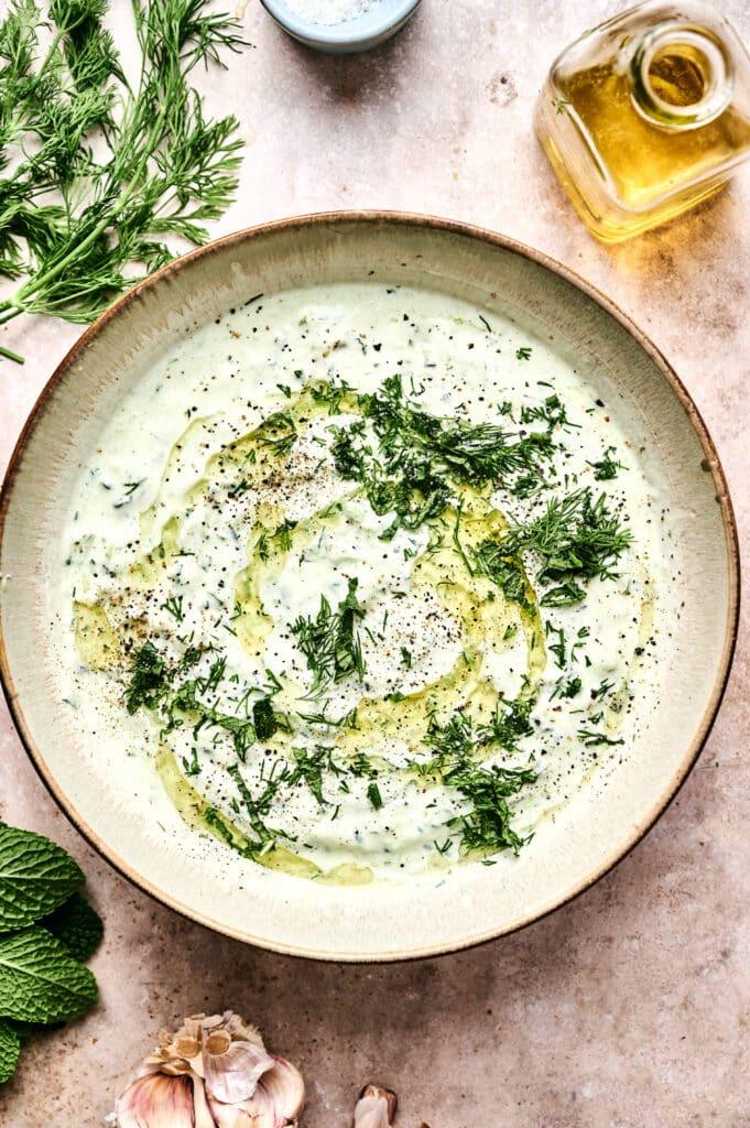 a bowl of homemade tzatziki sauce with fresh herbs
