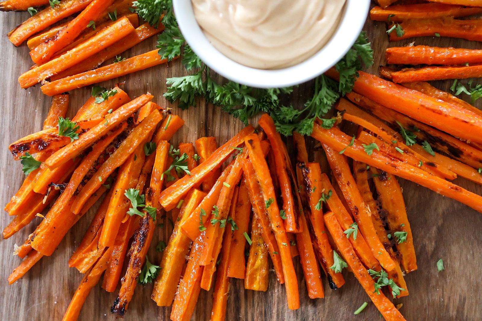 close-up shot of teriyaki glazed carrot fries on a wooden board