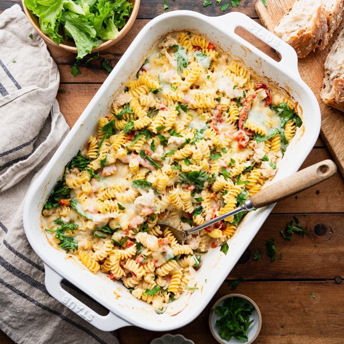 A family enjoying Creamy Tuscan Chicken Pasta Bake around a dinner table