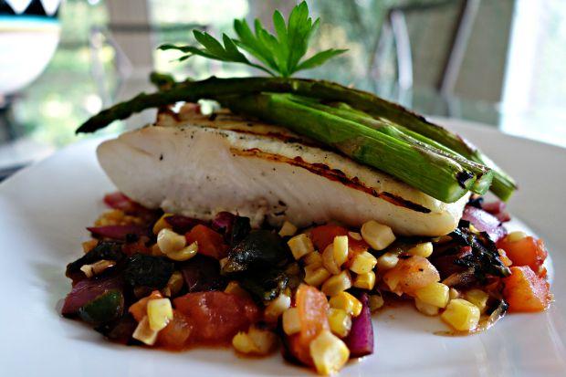 close up of grilled halibut being topped with corn salsa