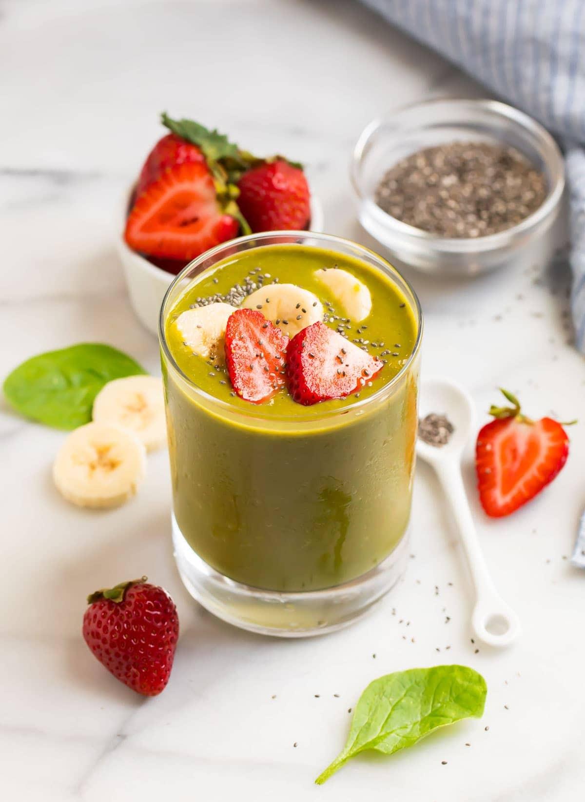 vibrant green strawberry spinach smoothie with pumpkin seeds