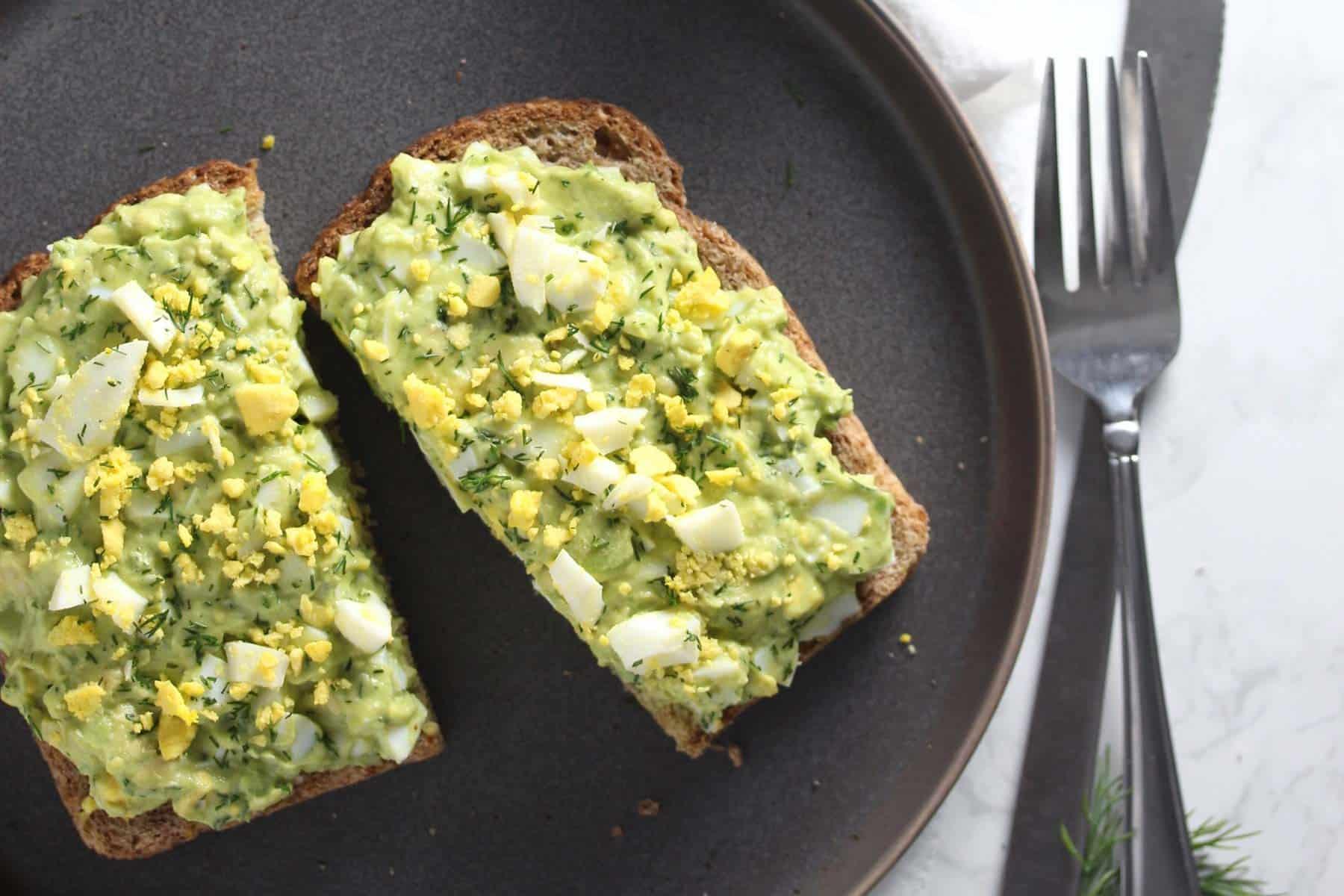 avocado egg salad being spread on whole wheat toast