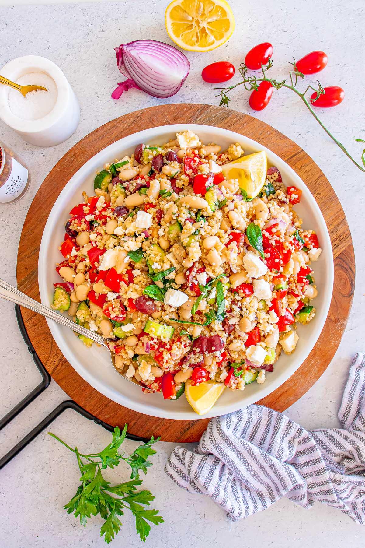 Ingredients for Greek pasta salad with quinoa and parsley arranged on a wooden table