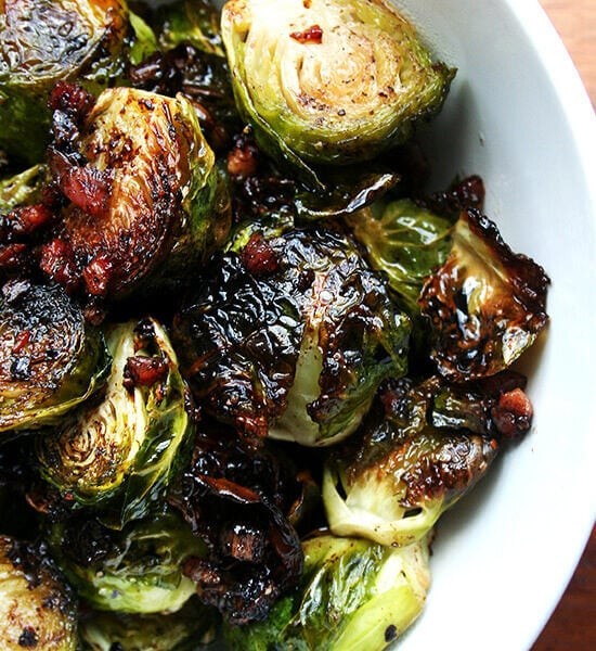 Vibrant close-up of perfectly roasted Brussels sprouts glistening with balsamic glaze in a rustic serving bowl, garnished with fresh herbs
