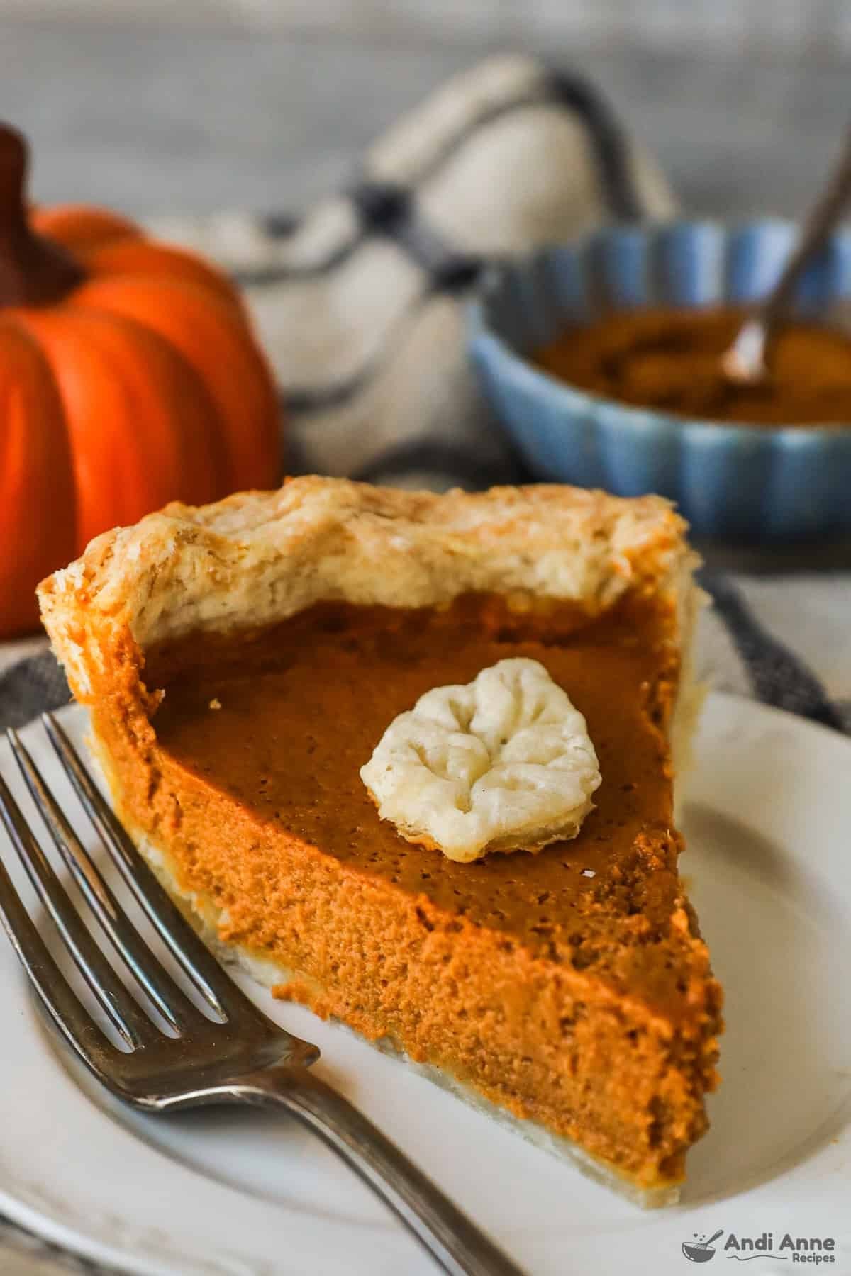 slice of creamy pumpkin pie with flaky butter crust, whipped cream, autumn decor, rustic table