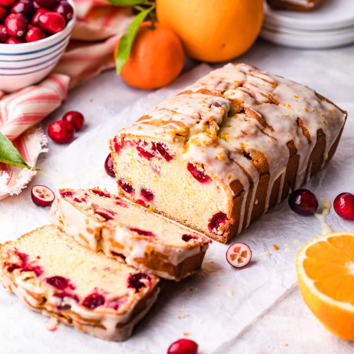 freshly baked cranberry orange bread loaf with vibrant citrus glaze drizzled on top, festive and cozy kitchen setting, natural light