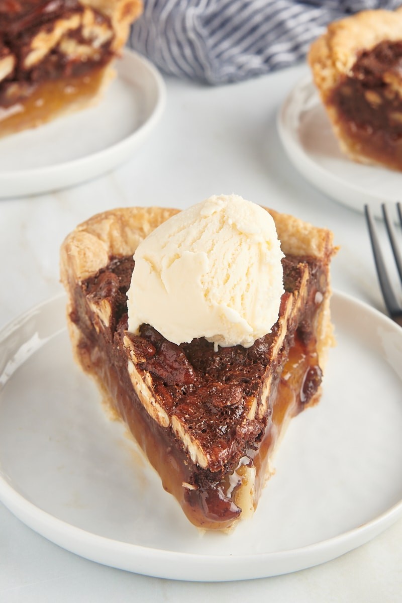 Decadent fudgy chocolate pecan pie slice with a scoop of vanilla ice cream