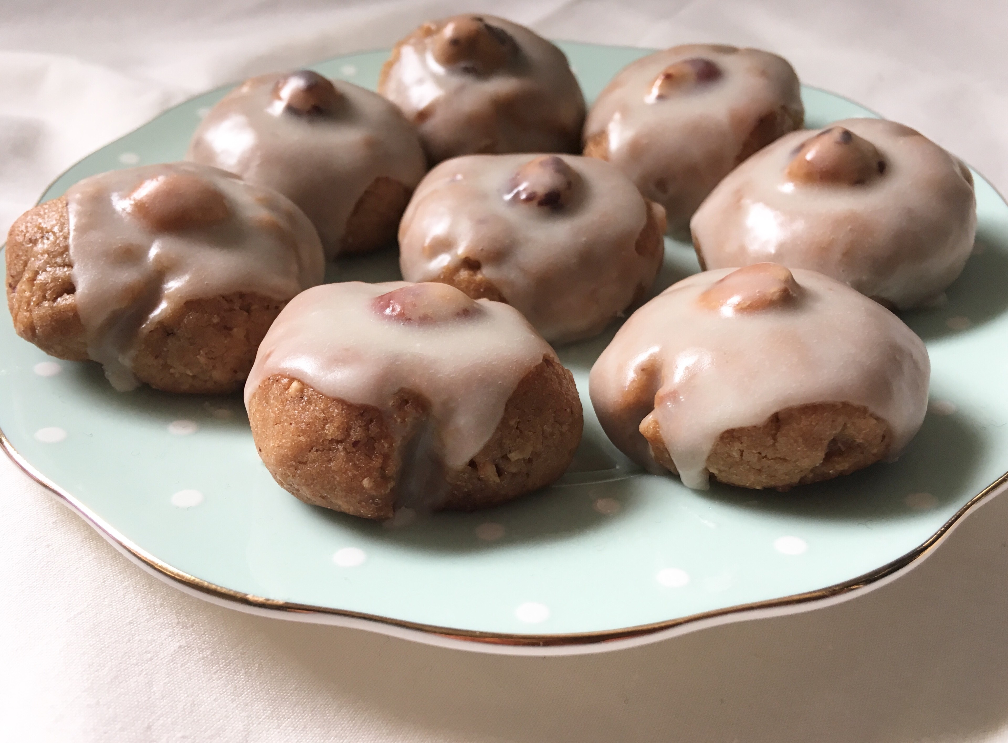 Rustic plate of golden brown hazelnut cookies, dusted with powdered sugar, a scattering of whole hazelnuts