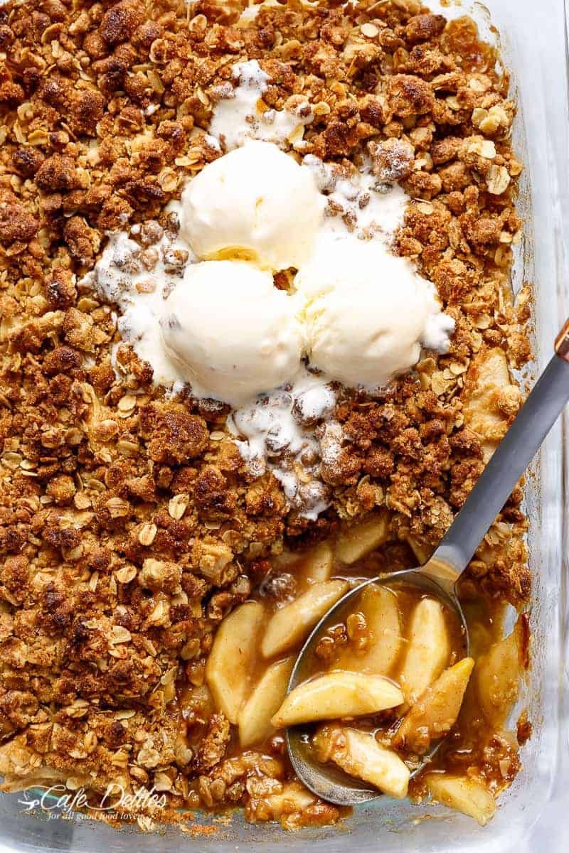 Delicious apple crumble with cinnamon crust, served warm with ice cream, autumn colors in background.
