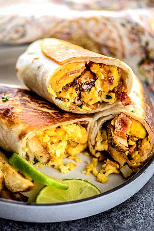 Close-up of a golden-brown, cheesy breakfast burrito melt with a vibrant salsa drizzle, avocado slices, and fresh cilantro