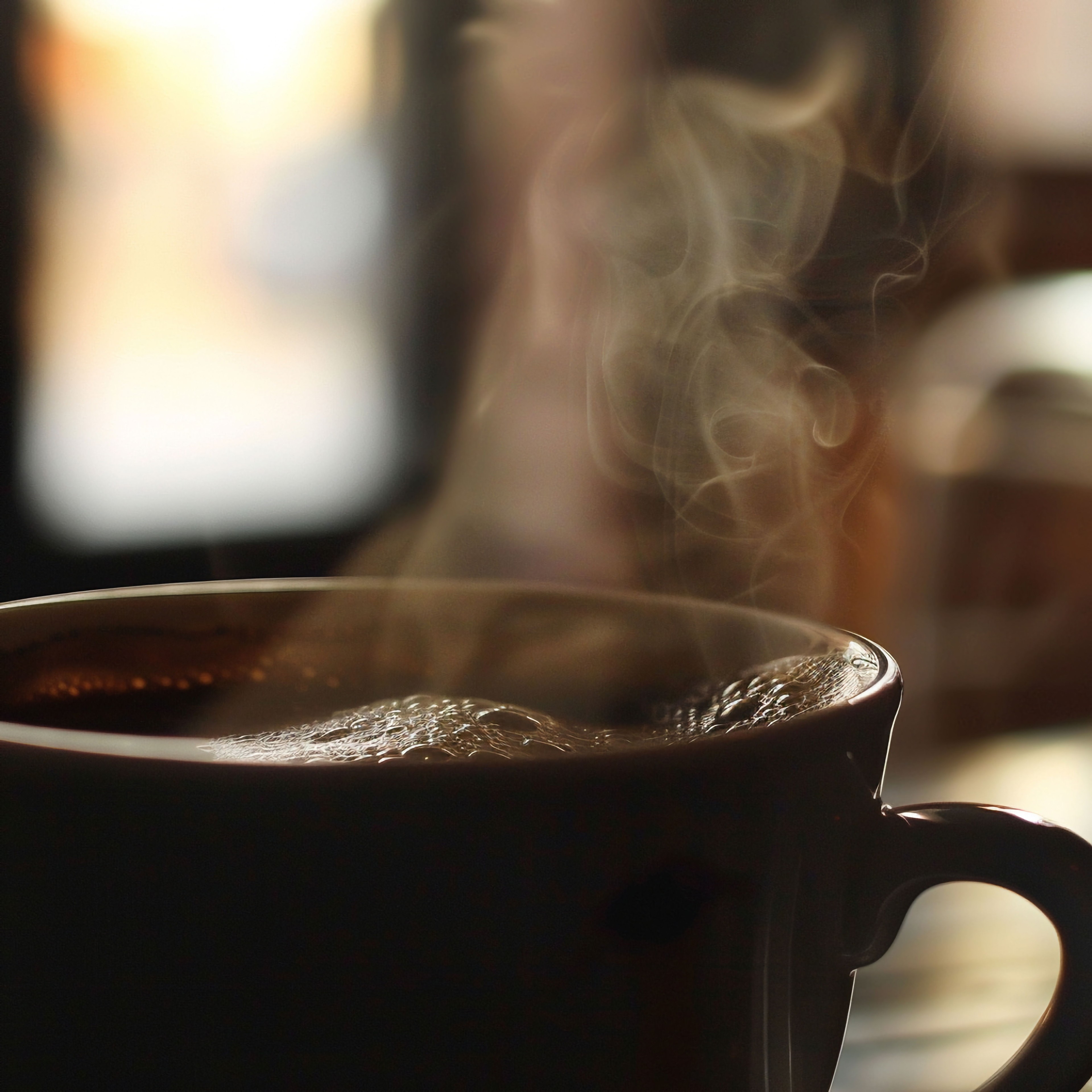 A person holding a warm mug of coffee, with soft morning light, and a plate of golden-brown espresso shortbread cookies on a rustic wooden table.