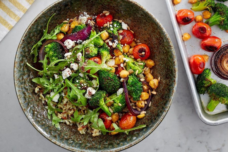 A vibrant bowl filled with roasted vegetables, chickpeas, and a tahini dressing