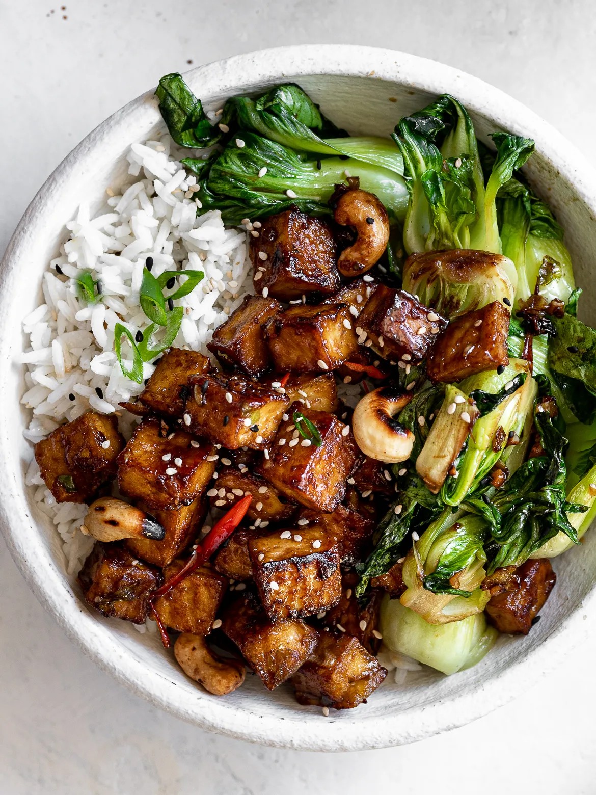 tofu and bok choy stir-fry in a wok with soy sauce and scallions
