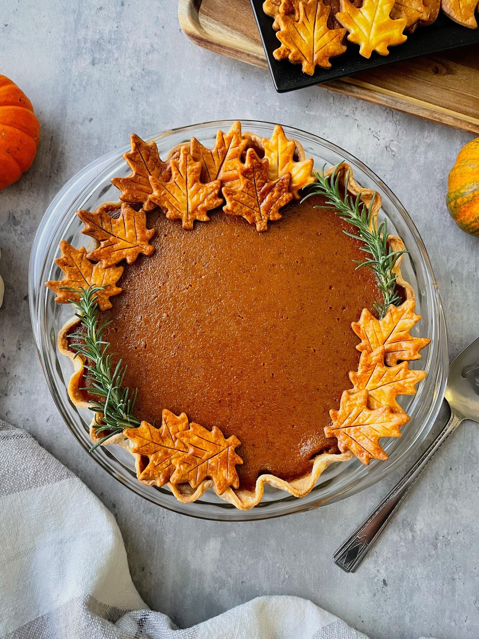 Golden top pumpkin pie cooling on a wire rack, autumn leaves in background, warm kitchen light